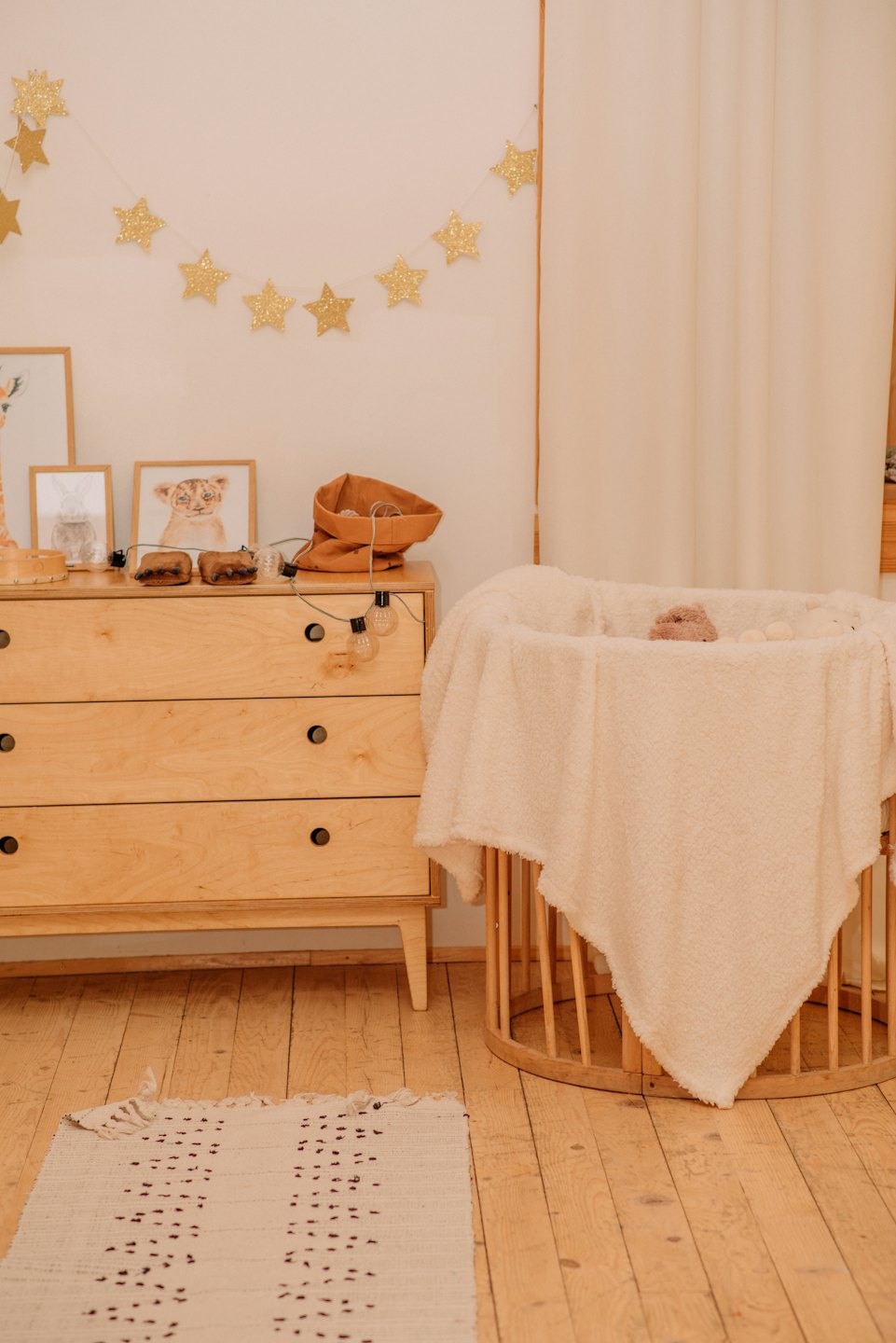 Een houten commode en wieg in een knusse babykamer.