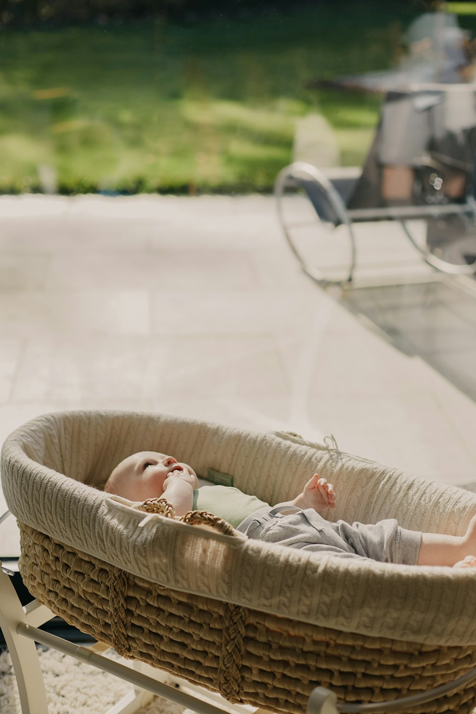 Een baby ligt in een rieten wieg met gebreide voering.